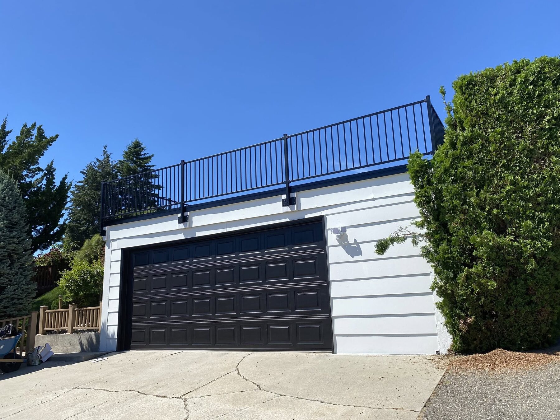 Black aluminum railing installed along a driveway and retaining wall