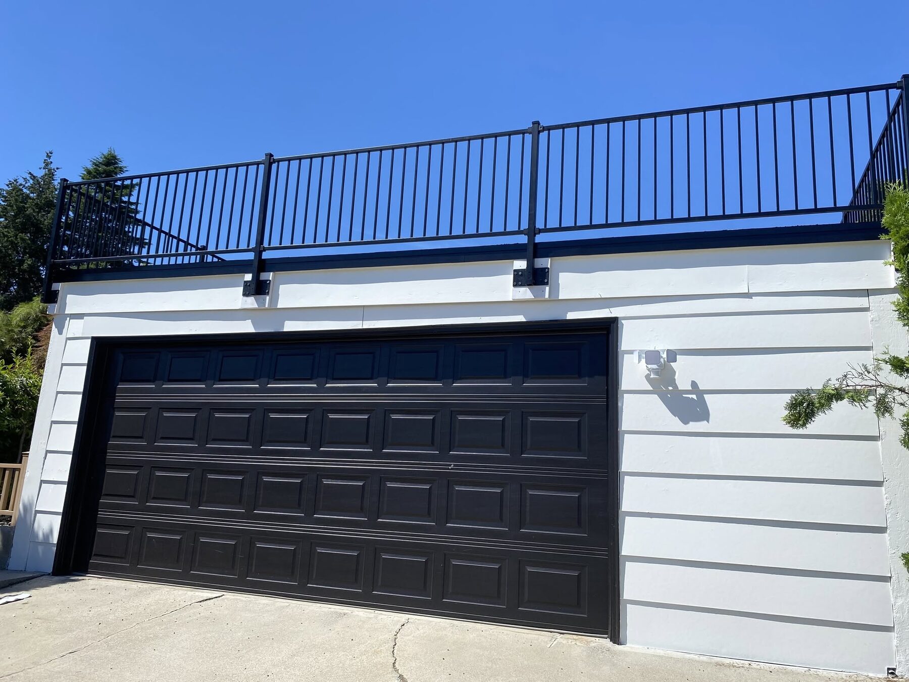 Black aluminum railing installed along a driveway and retaining wall