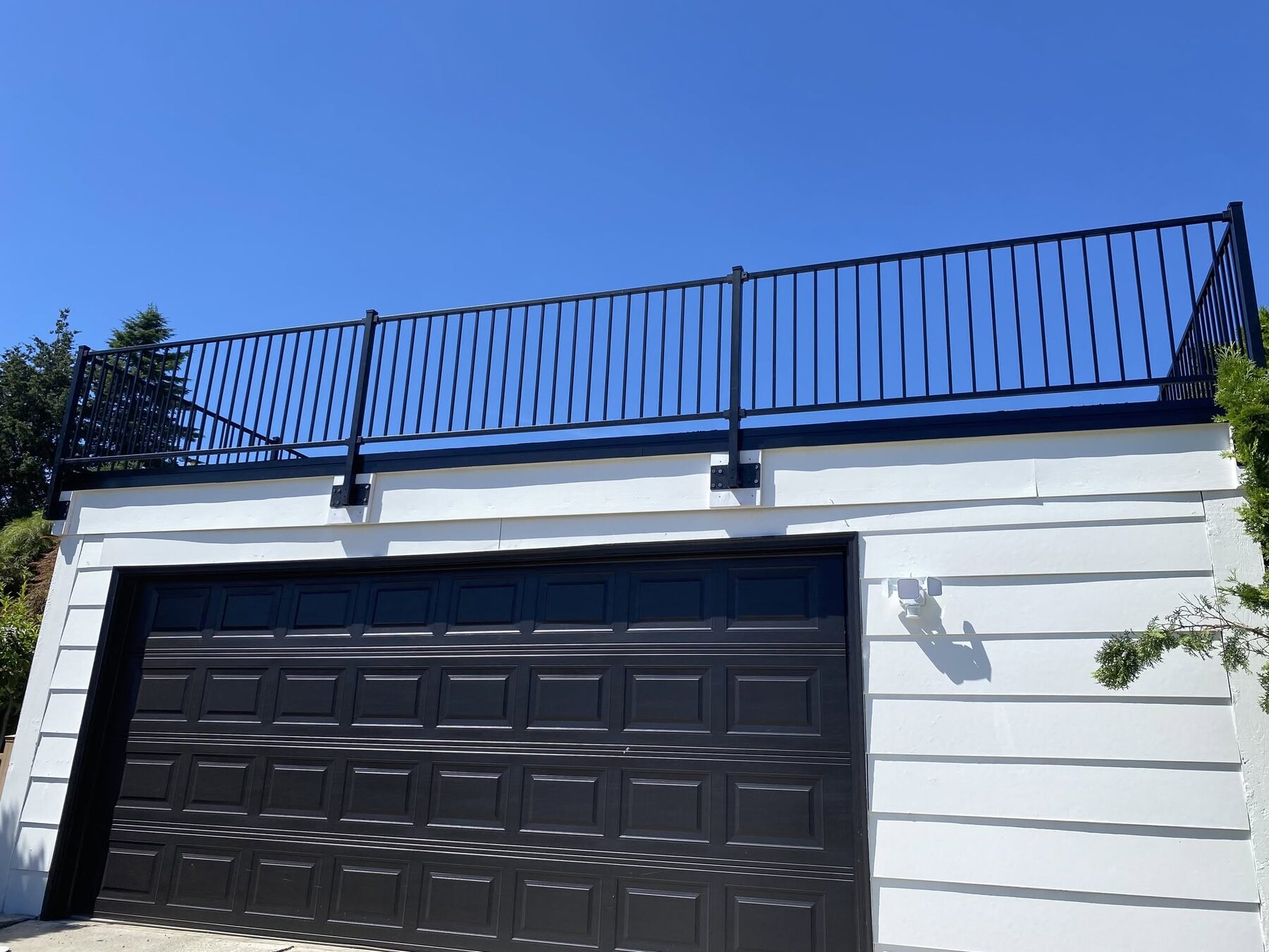 Black aluminum railing installed along a driveway and retaining wall