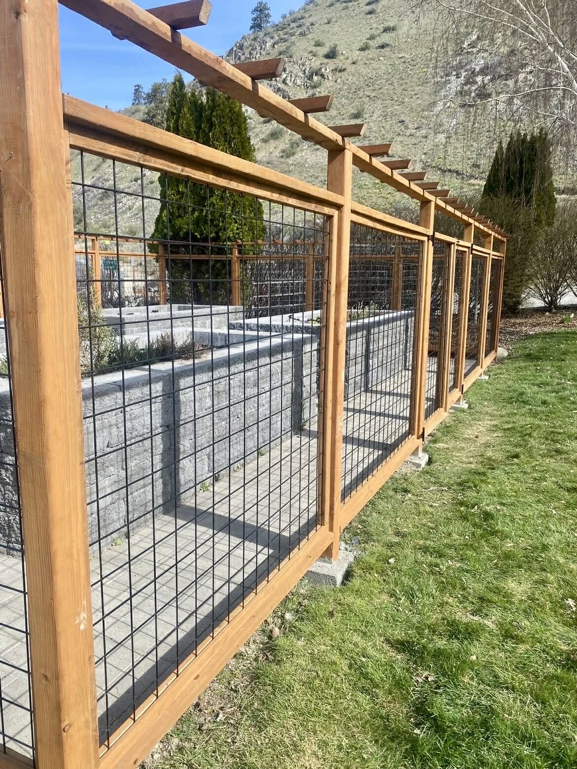 Deer proof garden enclosure with hog wire panels and a cedar pergola top in Chelan